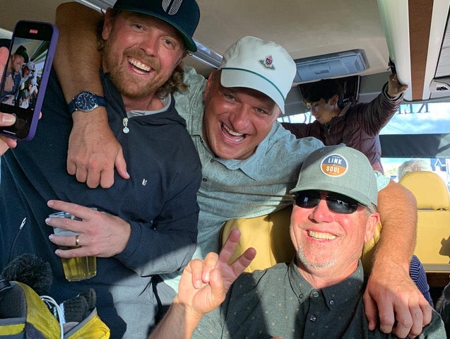 Three men inside a vehicle, smiling and posing for a photo.